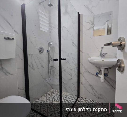 מקלחון פינתי מזכוכית עם פרופיל שחור בחדר רחצה מעוצב